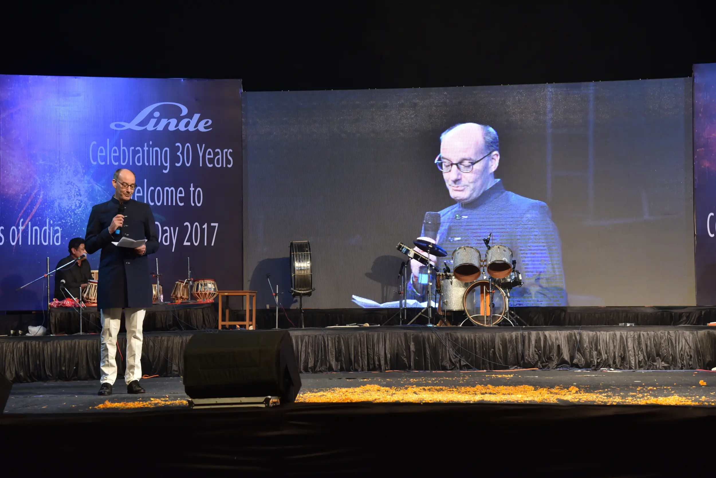 Man and woman speaking on stage at night with blue lighting